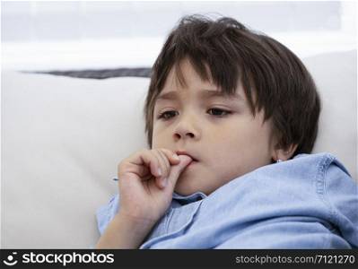 Portrait of little boy biting his finger nails while watching TV, Childhood and family concept, Emotional Child portrait.