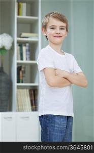 Portrait of little boy in casuals standing with arms crossed at home