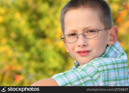 portrait of little boy in early fall park. he is looking at camera.
