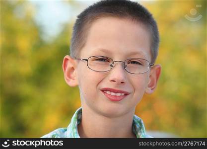 portrait of little boy in early fall park. he is looking at camera and smiling