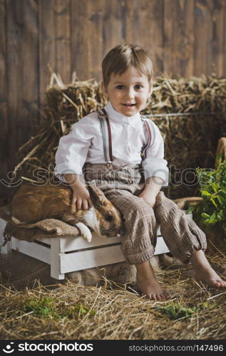 Portrait of little boy playing with a rabbit.. Portrait of baby with Bunny of hay and white boxes 6042.