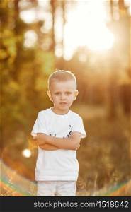 Portrait of little boy with blond hair and a white shirt near. portrait at sunset.. Portrait of little boy with blond hair and a white shirt near. portrait at sunset