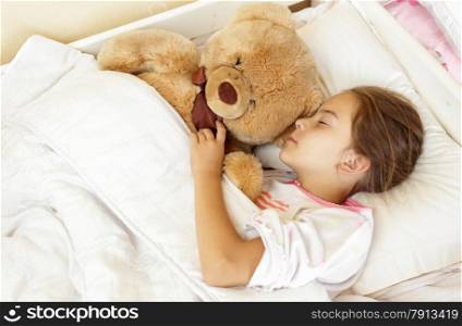 Portrait of little brunette girl sleeping in bed with teddy bear