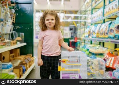 Portrait of little girl child standing nearby cage for rodent at pet shop. Choosing home for domestic animal. Portrait of little girl child standing nearby cage for rodent at pet shop