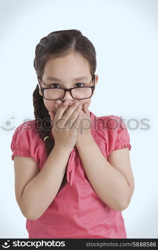 Portrait of little girl covering mouth with hands