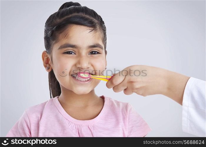 Portrait of little girl getting teeth brushed
