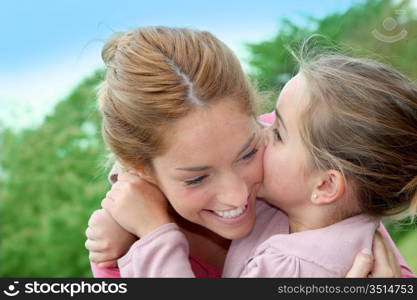 Portrait of little girl giving kiss to her mom