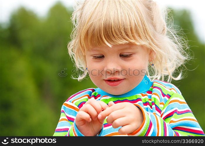 Portrait of little girl in stripe clothe with earrings in park. A close up.