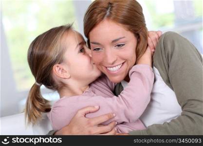 Portrait of little girl kissing her mom