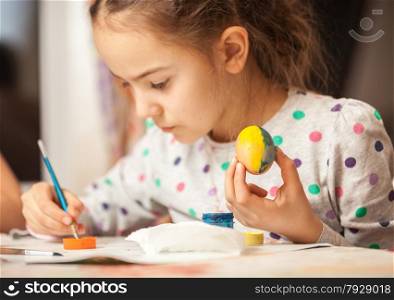 Portrait of little girl painting egg on christian easter