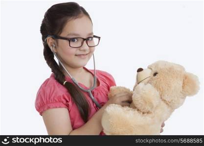 Portrait of little girl playing doctor with teddy bear