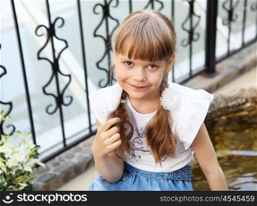 portrait of little girl sitting alone outdoors