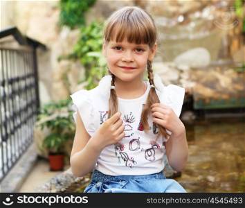 portrait of little girl sitting alone outdoors