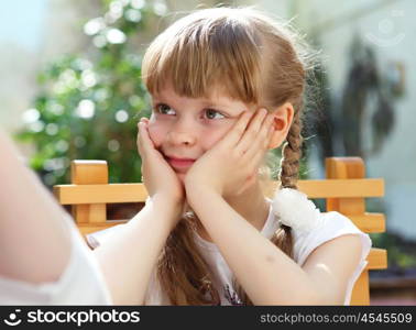 portrait of little girl sitting alone outdoors