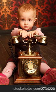 Portrait of little girl sitting with retro phone. Interior in retro style. Vertical format.