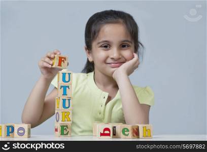 Portrait of little girl stacking blocks isolated over blue background