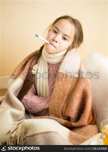 Portrait of little girl with chickenpox holding thermometer in mouth