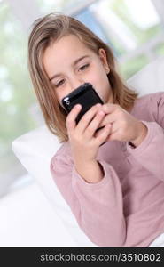 Portrait of little girl writing short message on mobile phone