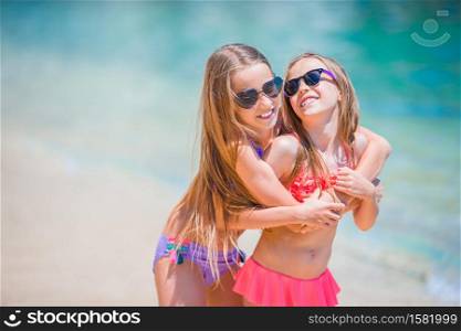 Portrait of little girls on the beach. Little happy funny girls have a lot of fun at tropical beach playing together.