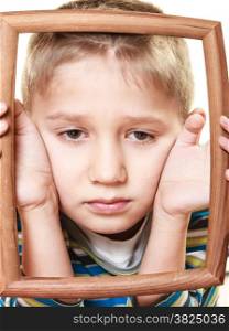 Portrait of little sad blonde boy child holding photo frame framing his face looking up studio shot isolated on white