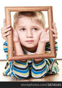 Portrait of little sad blonde boy child holding photo frame framing his face looking up studio shot isolated on white