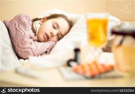 Portrait of little sick girl in sweater sleeping in bed