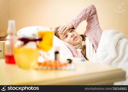Portrait of little sick girl with high temperature lying in bedroom