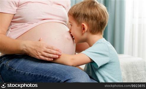 Portrait of little toddler boy talking to baby in pregnant mother belly. Family expecting a baby. Portrait of little toddler boy talking to baby in pregnant mother belly. Family expecting a baby.