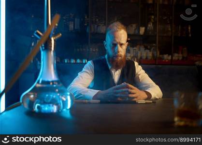 Portrait of lonely bearded man sitting at table and smoking hookah while drinking brandy alcohol. Portrait of lonely bearded man smoking hookah and drinking brandy