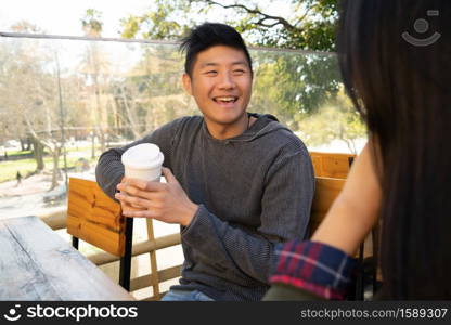 Portrait of lovely asian couple having good time and talking to each other in coffee shop.