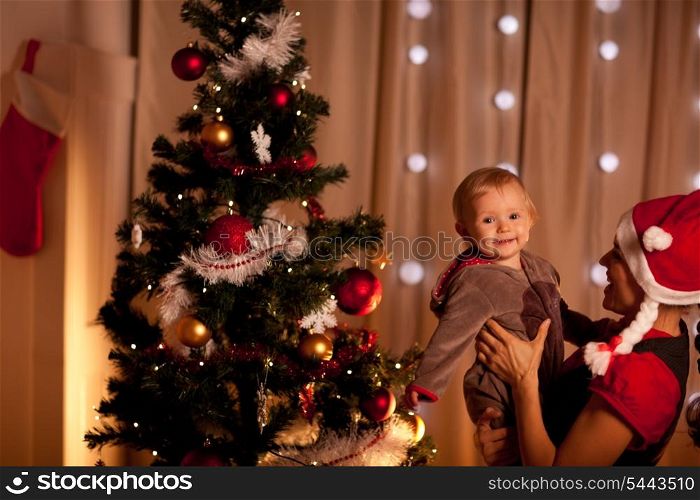Portrait of lovely baby on mamas hand near Christmas tree&#xA;