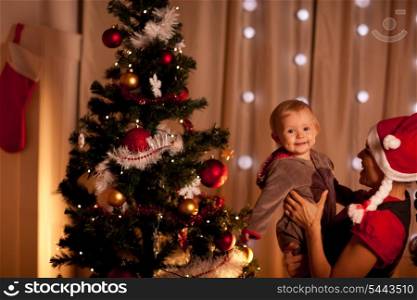 Portrait of lovely baby on mamas hand near Christmas tree&#xA;