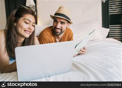 Portrait of lovely couple organizing their trip with a laptop at the hotel room. Travel and holiday concept.