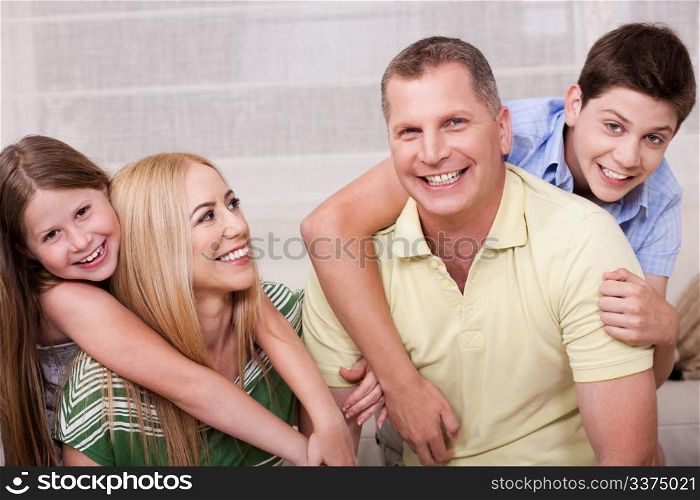 Portrait of lovely family having fun together in living room and looking at you