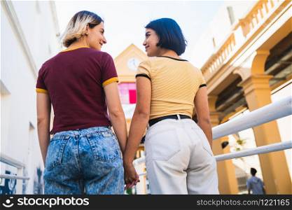 Portrait of lovely lesbian couple spending time together and holding hands at the street. LGBT concept.