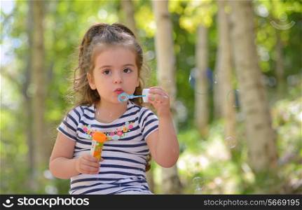 Portrait of lovely little girl blowing soap bubbles