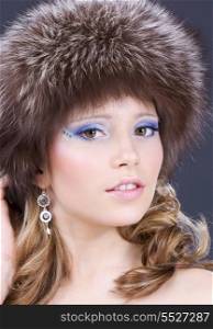 portrait of lovely woman in furry hat over grey
