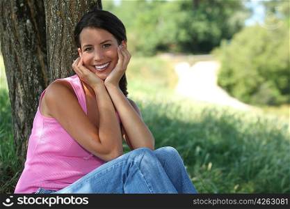 portrait of lovely young brunette posing in park with face in her hands