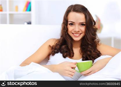 Portrait of lovely young woman having cup of tea at home