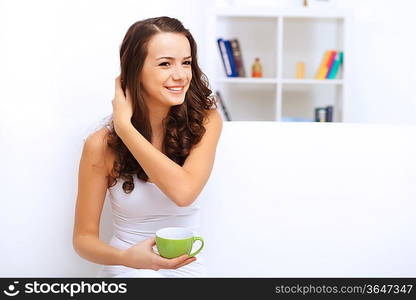 Portrait of lovely young woman having cup of tea at home