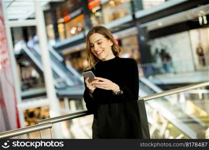 Portrait of lovely young woman looking on mobile phone in shopping center