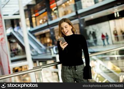 Portrait of lovely young woman looking on mobile phone in shopping center