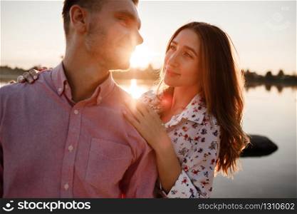 portrait of loving couple hugging on the lake at sunset. Beautiful man and woman in love walking on the shore of the lake at sunset. copy space. selective focus.. portrait of loving couple hugging on the lake at sunset. Beautiful man and woman in love walking on the shore of the lake at sunset. copy space. selective focus