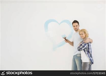 Portrait of loving mid-adult couple with painted heart on wall