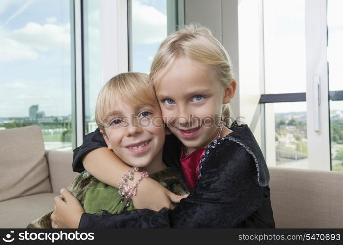 Portrait of loving siblings in dinosaur and vampire costumes at home