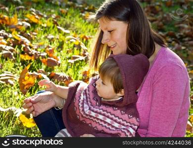 Portrait of loving young mother holding her baby in autumn park