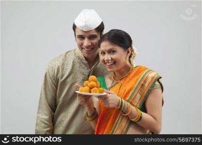 Portrait of Maharashtrian couple holding plate of laddoos