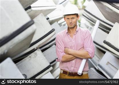 Portrait of male architect holding rolled up blueprint at construction site