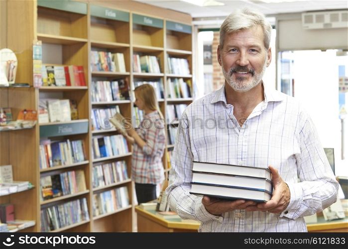 Portrait Of Male Bookstore Owner With Customer In Background