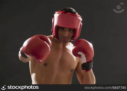 Portrait of male boxer wearing gloves and head protector isolated over black background